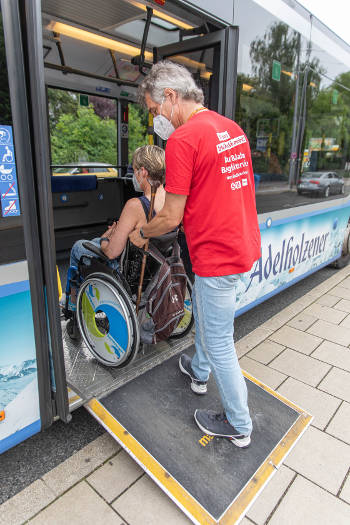 Ein Rollstuhl wird über eine Rampe in einen Bus geschoben