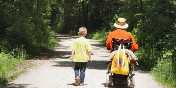 Wandern - eine Rollstuhlfahrerin und ein Kind auf einem Wanderweg